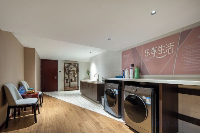 A modern kitchen with a built-in washing machine, a dining area with chairs, and a wooden floor.