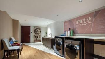 A modern kitchen with a built-in washing machine, a dining area with chairs, and a wooden floor.