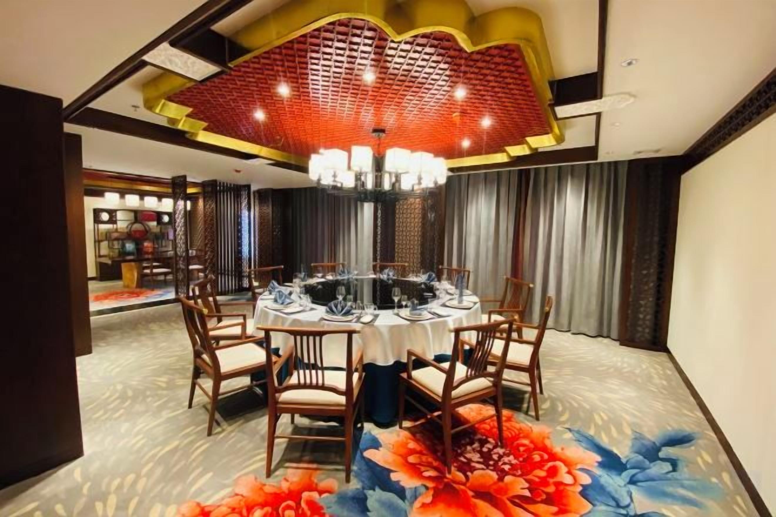 A dining area with a round table, chairs, and a chandelier.
