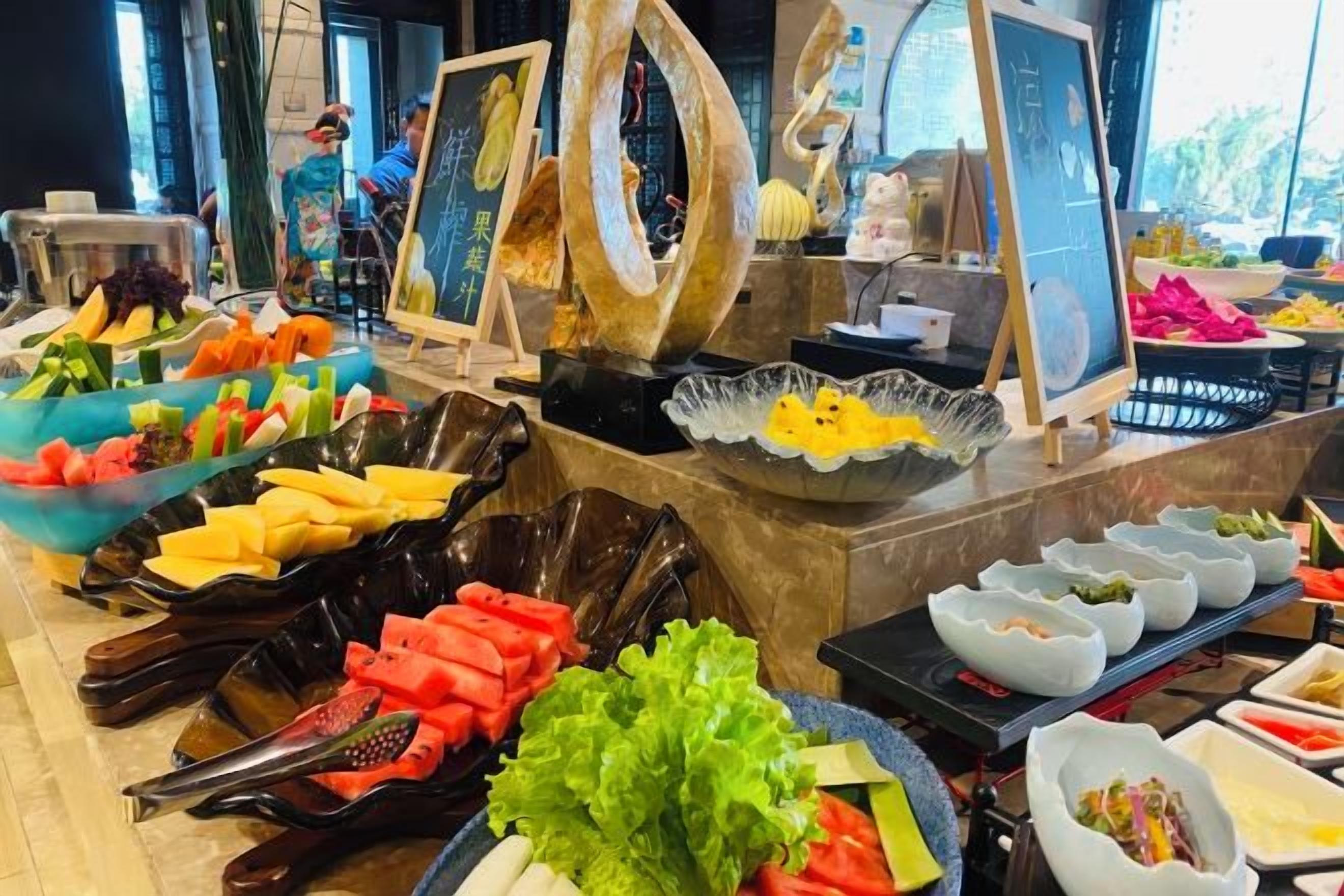 A buffet with various food items and a large decorative sculpture.