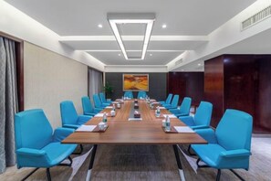 A conference room with a long table, blue chairs, and a painting on the wall. - Shuiyi Boqing Hotel (Heze)