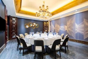 Un salón de conferencias con una mesa redonda, sillas y un candelabro.