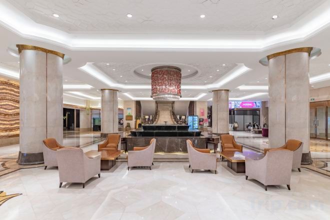 A spacious lobby with marble flooring, a central fountain, and seating areas.