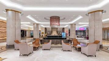 A spacious lobby with marble flooring, a central fountain, and seating areas.