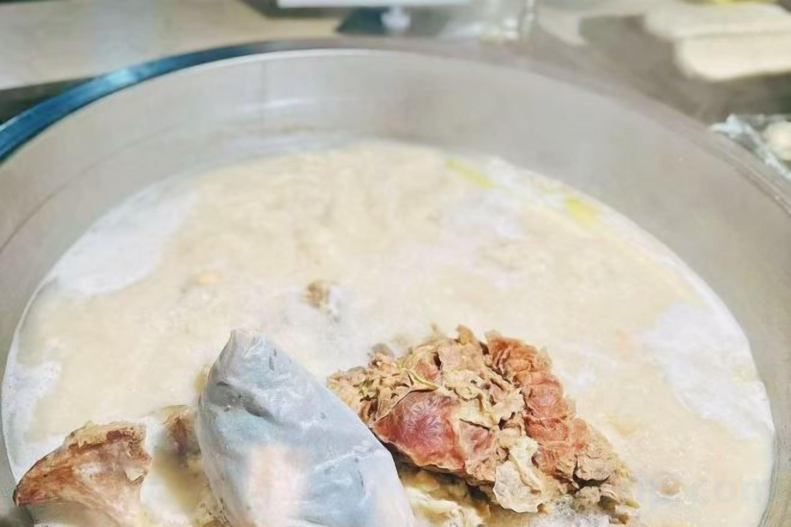 A bowl containing a creamy mixture with a fish head and cereal flakes.