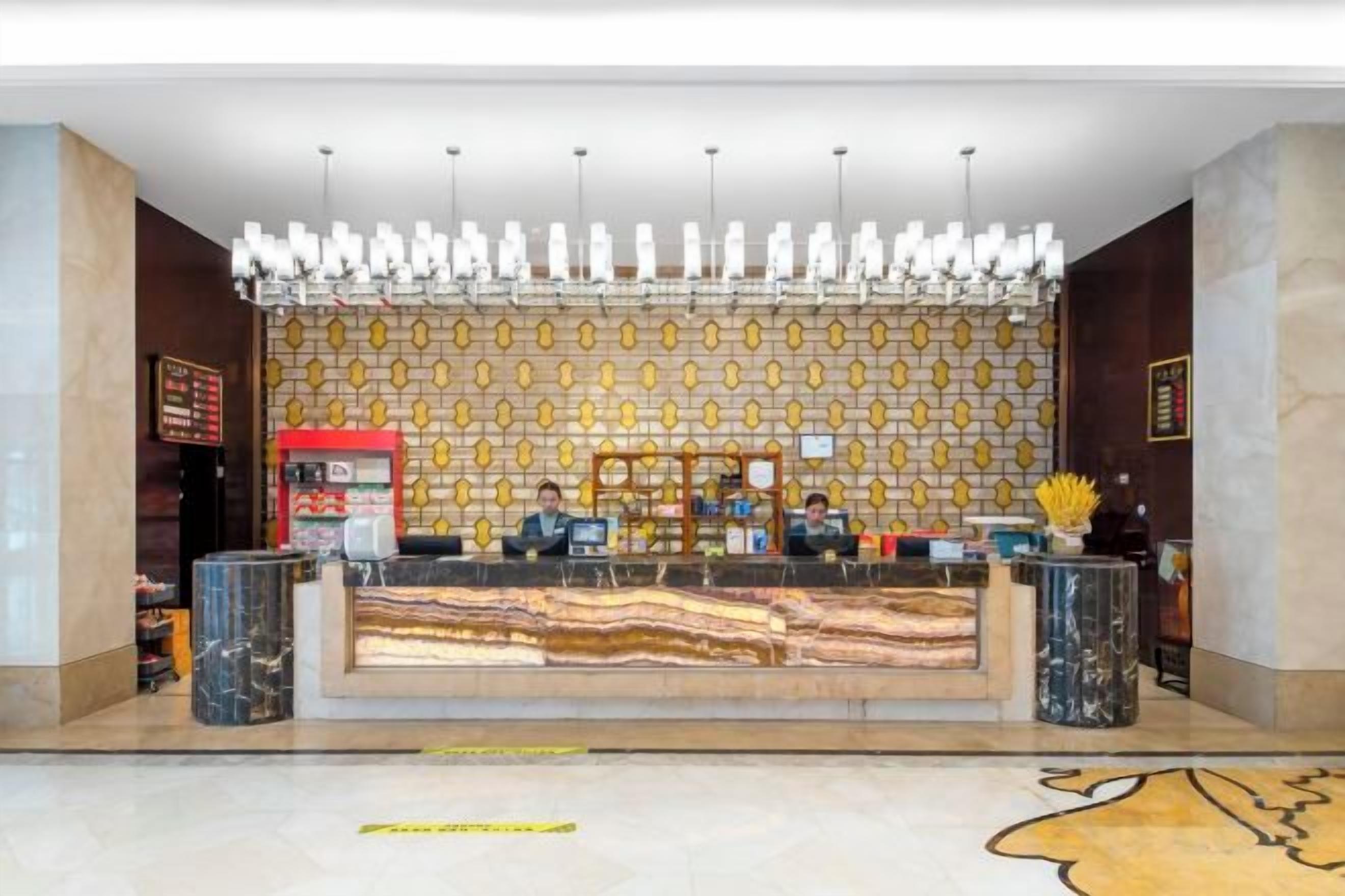 A reception desk with a patterned wall and a chandelier.