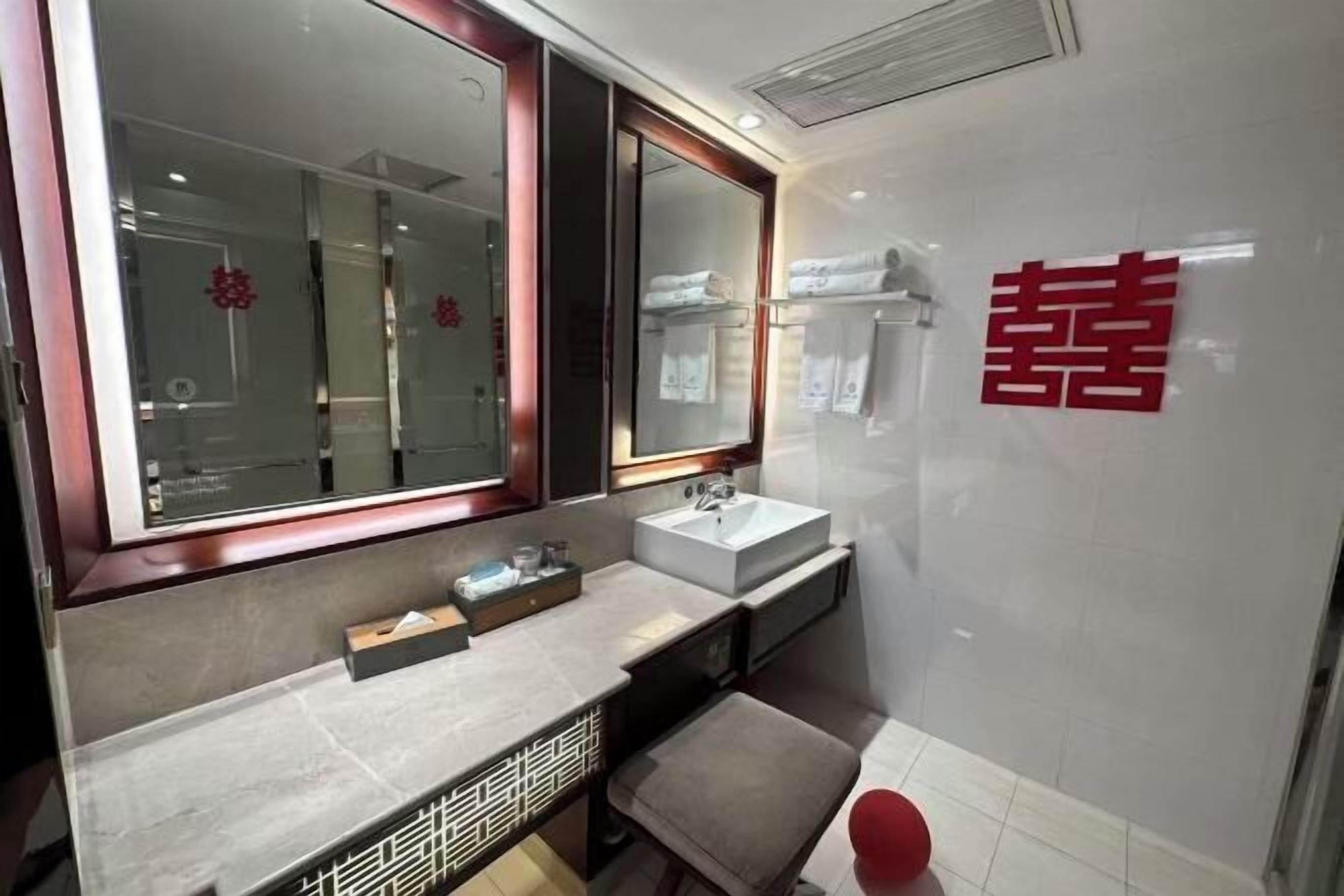 Un baño moderno con un espejo grande, un lavamanos y un banco.
