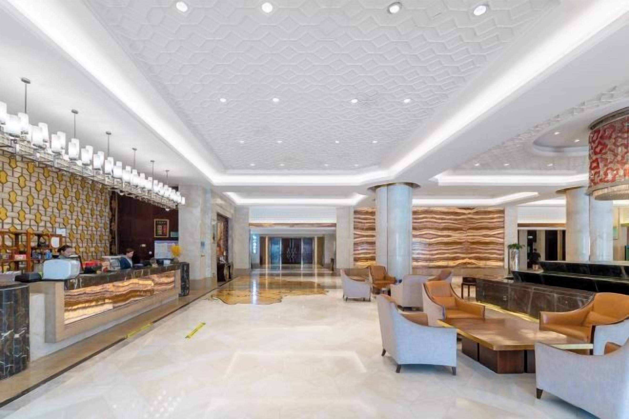 A spacious lobby with a reception desk, seating area, and a patterned wall.