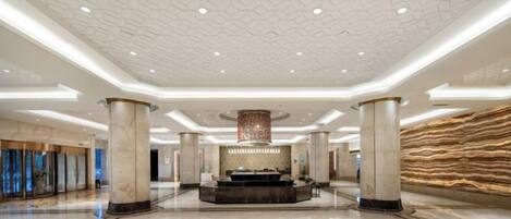 A spacious lobby with a central fountain, high ceilings, and marble flooring.