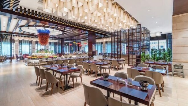 A spacious dining area with multiple tables and chairs, a modern ceiling design, and a view of the outdoors. - Shuiyi Boqing Hotel (Heze)