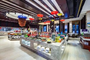 Un restaurante moderno con una isla central de exhibición, decoraciones colgantes y una zona de estar con mesas.
