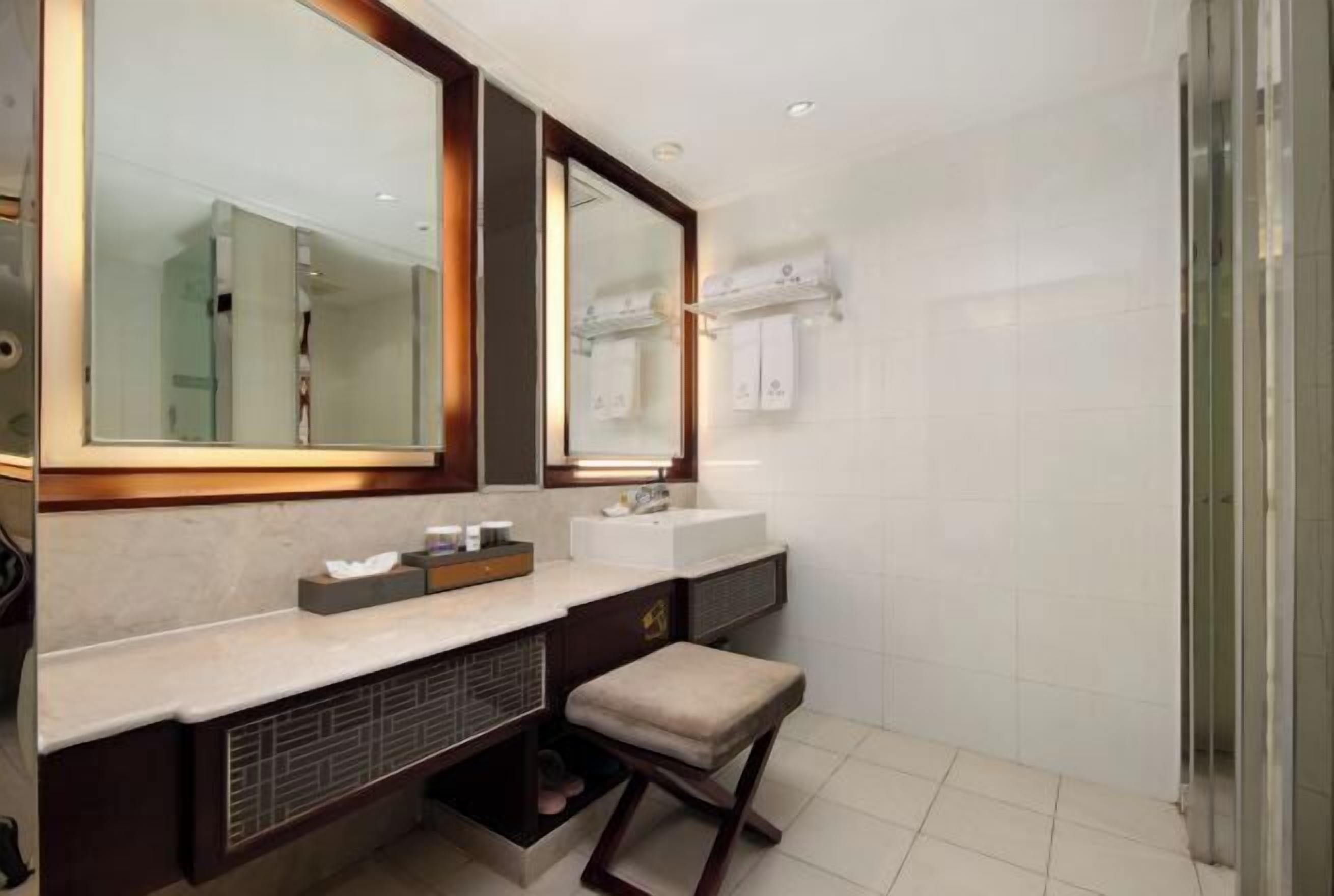 Un baño moderno con un espejo grande, dos lavamanos, un mueble de tocador y una zona de ducha.
