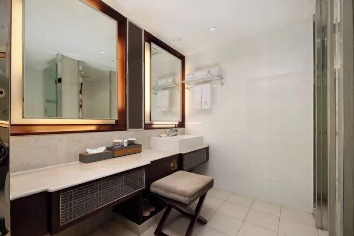 Un baño moderno con un espejo grande, dos lavamanos, un mueble de tocador y una zona de ducha.
