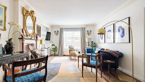 A well-lit living room with a wooden floor, a blue sofa, a coffee table, and a TV on a stand.