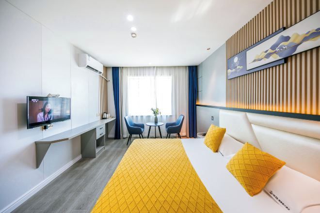 Habitación de hotel con cama, televisión, escritorio y silla.