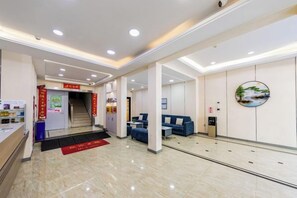 A hotel lobby with a reception desk, a staircase, seating area, and a vending machine. - Naxiang Fujian Holiday Inn (Zhujiajian branch of Oriental Garden Hotel) (Zhoushan)
