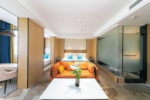 A modern hotel room with a sofa bed, a small table with a vase, a desk, and a glass partition. - Naxiang Fujian Holiday Inn (Zhujiajian branch of Oriental Garden Hotel) (Zhoushan)