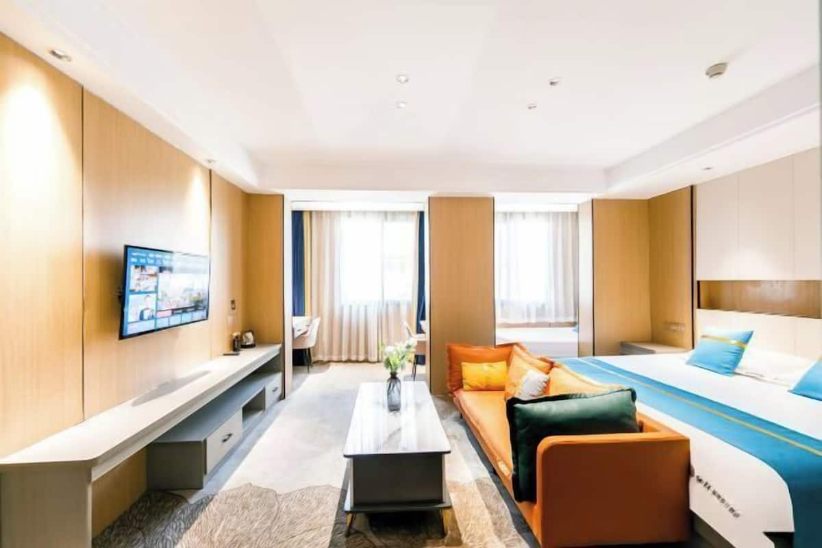 A hotel room with a bed, sofa, TV, and a small table.