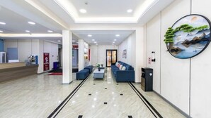 A modern lobby with a reception desk, seating area, and a large wall painting. - Naxiang Fujian Holiday Inn (Zhujiajian branch of Oriental Garden Hotel) (Zhoushan)
