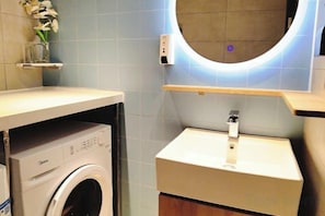 A compact bathroom with a washing machine, a sink, and a mirror with a circular light. - Homeinn Hotel (Dalian People's Square Xinkai Road) (Dalian)