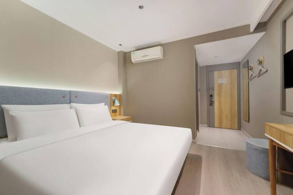 Quarto de hotel moderno com uma cama grande, mesas de cabeceira, uma escrivaninha e um espelho.