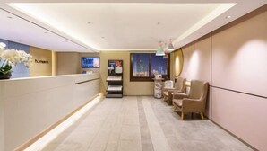 A hotel reception area with a reception desk, seating area, and a cityscape view through the window. - Homeinn Hotel (Dalian People's Square Xinkai Road) (Dalian)