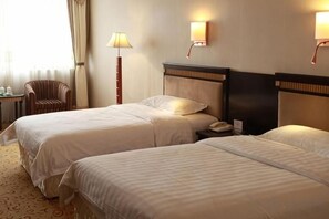 A hotel room with two beds, a bedside table, a lamp, and a chair. - Qingdao Huaxi Hotel (Qingdao)