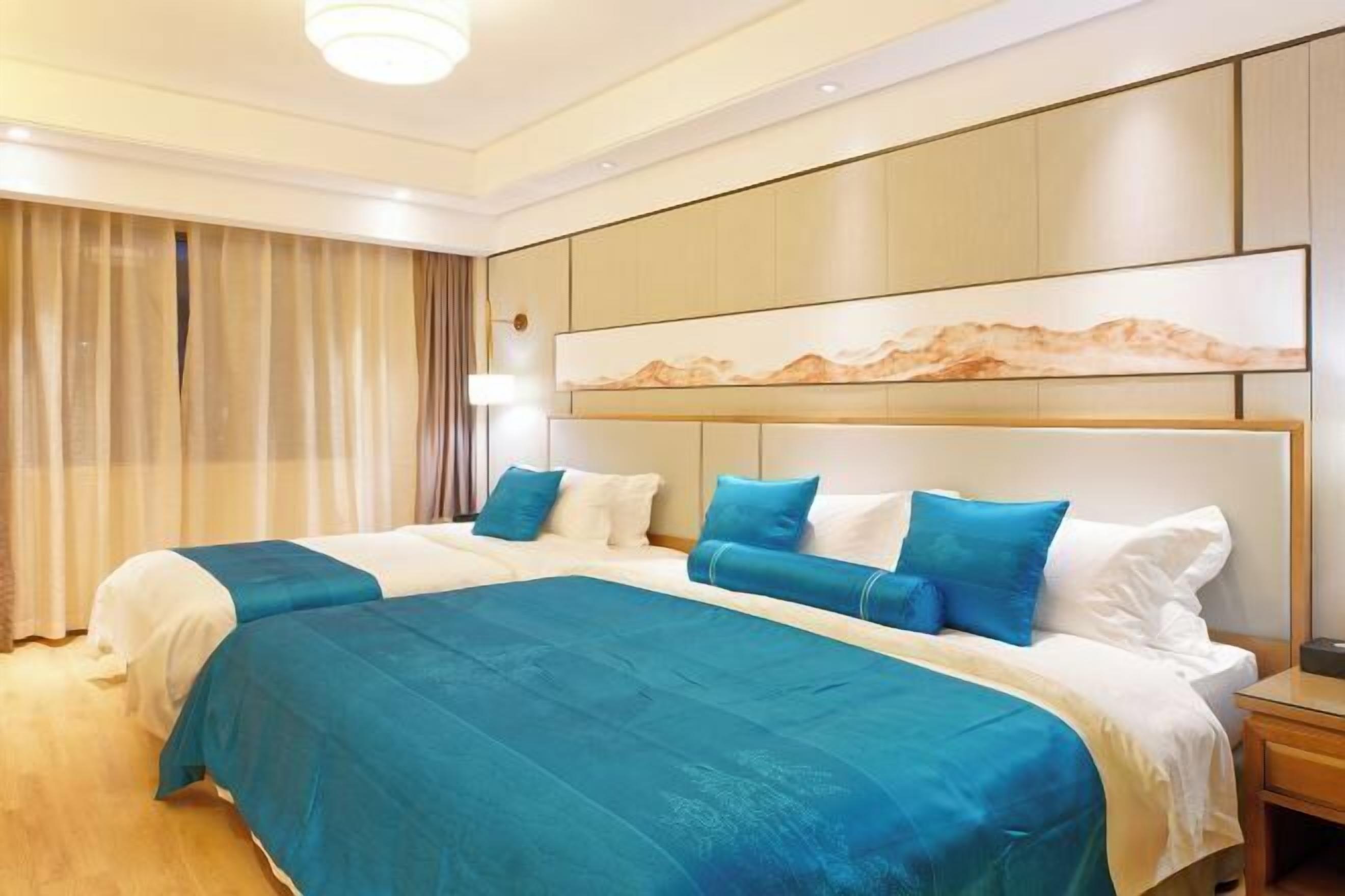 Una habitación de hotel con una cama grande, un cabecero con un cuadro y una mesita de noche.