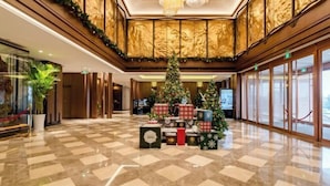 Een ontvangsthal met een grote kerstboom, cadeauverpakkingen en een receptiebalie.