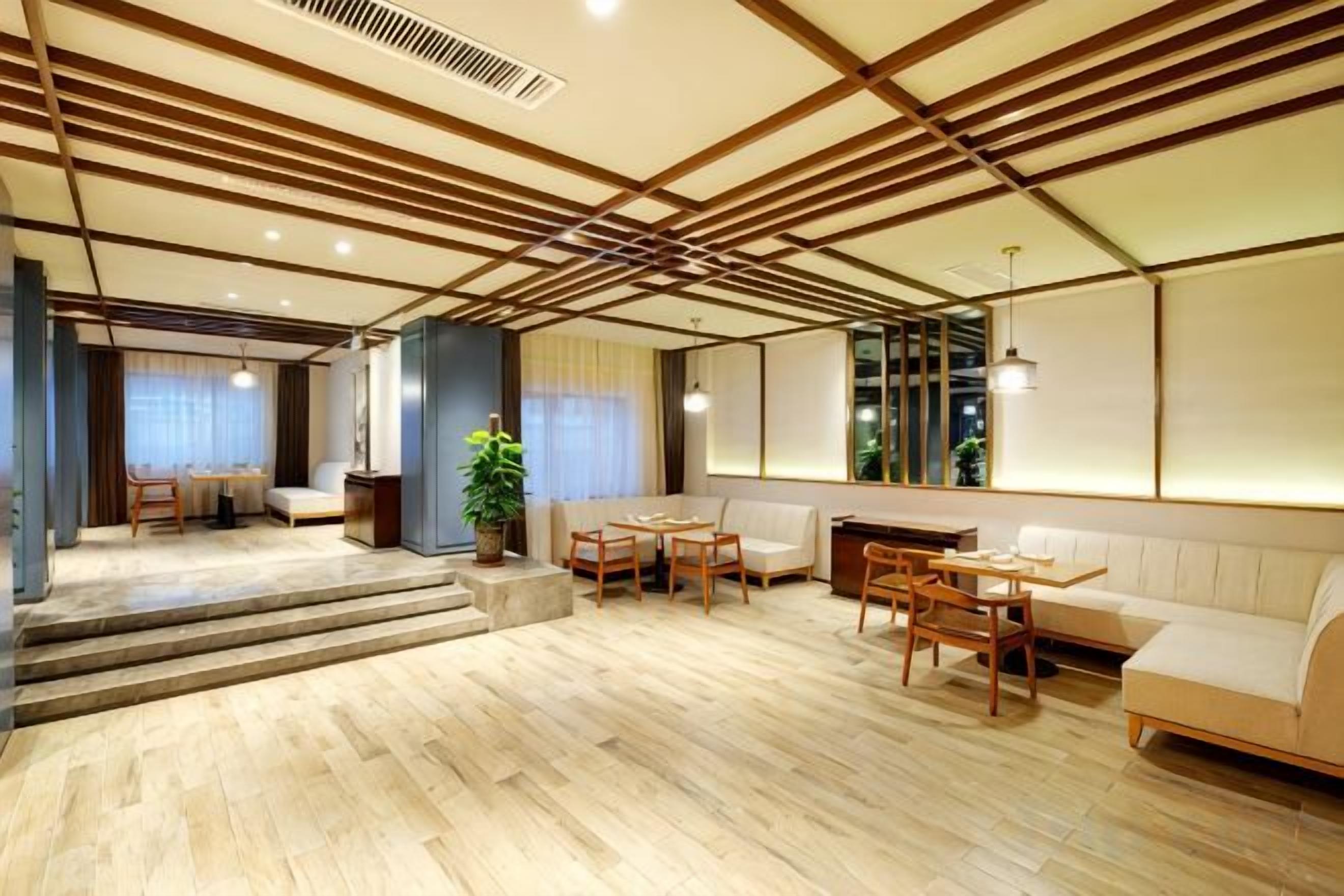 A modern interior with a wooden floor, a seating area with a sofa and chairs, and a staircase leading to another room.