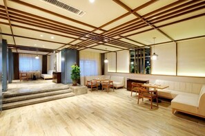 A modern interior with a wooden floor, a seating area with a sofa and chairs, and a staircase leading to another room. - Qingdao Huaxi Hotel (Qingdao)