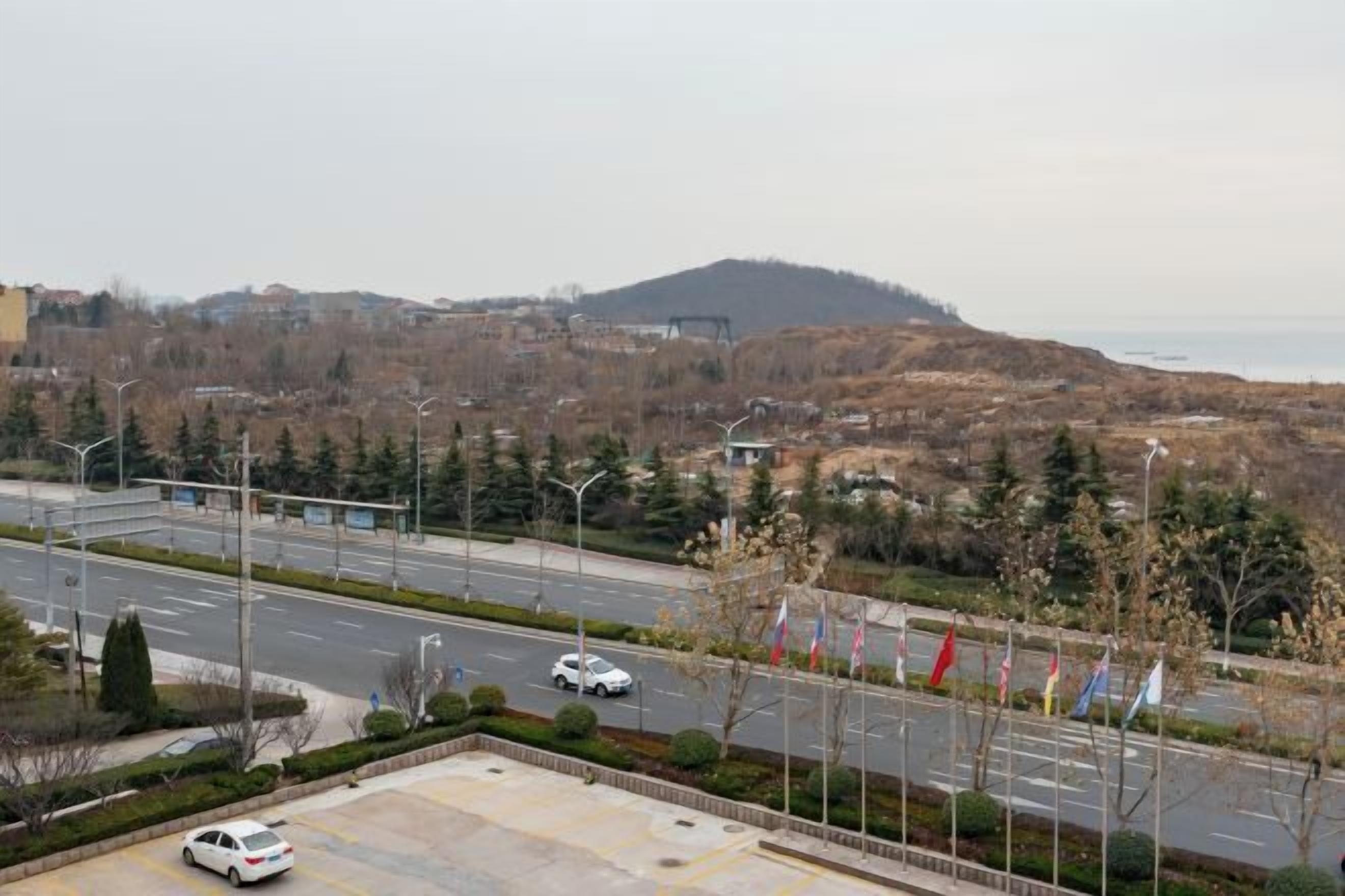 A road with a parking area and a view of a hilly landscape.