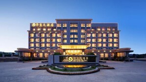 Een meerlaags hotel met een opvallende ingang en een goed verlichte gevel.