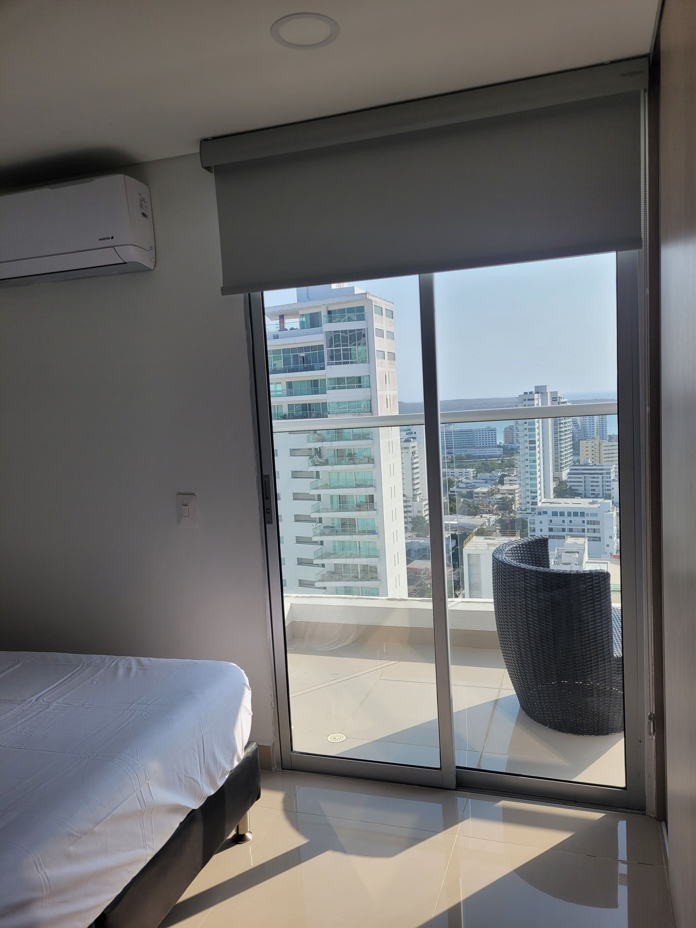 A modern bedroom with a large window, a bed, and a view of a cityscape.