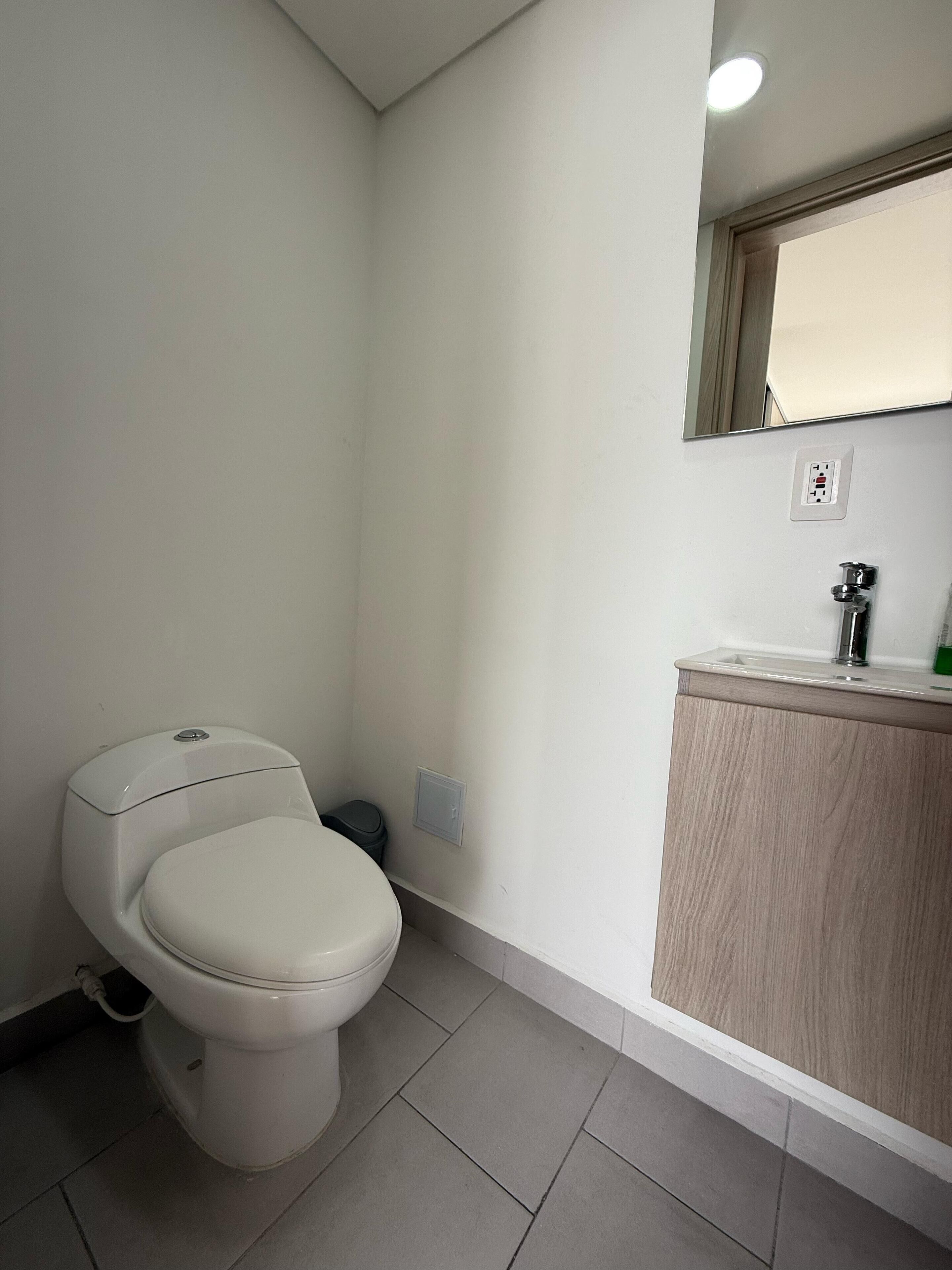 Un bagno piccolo e pulito con il water, un lavandino e uno specchio.