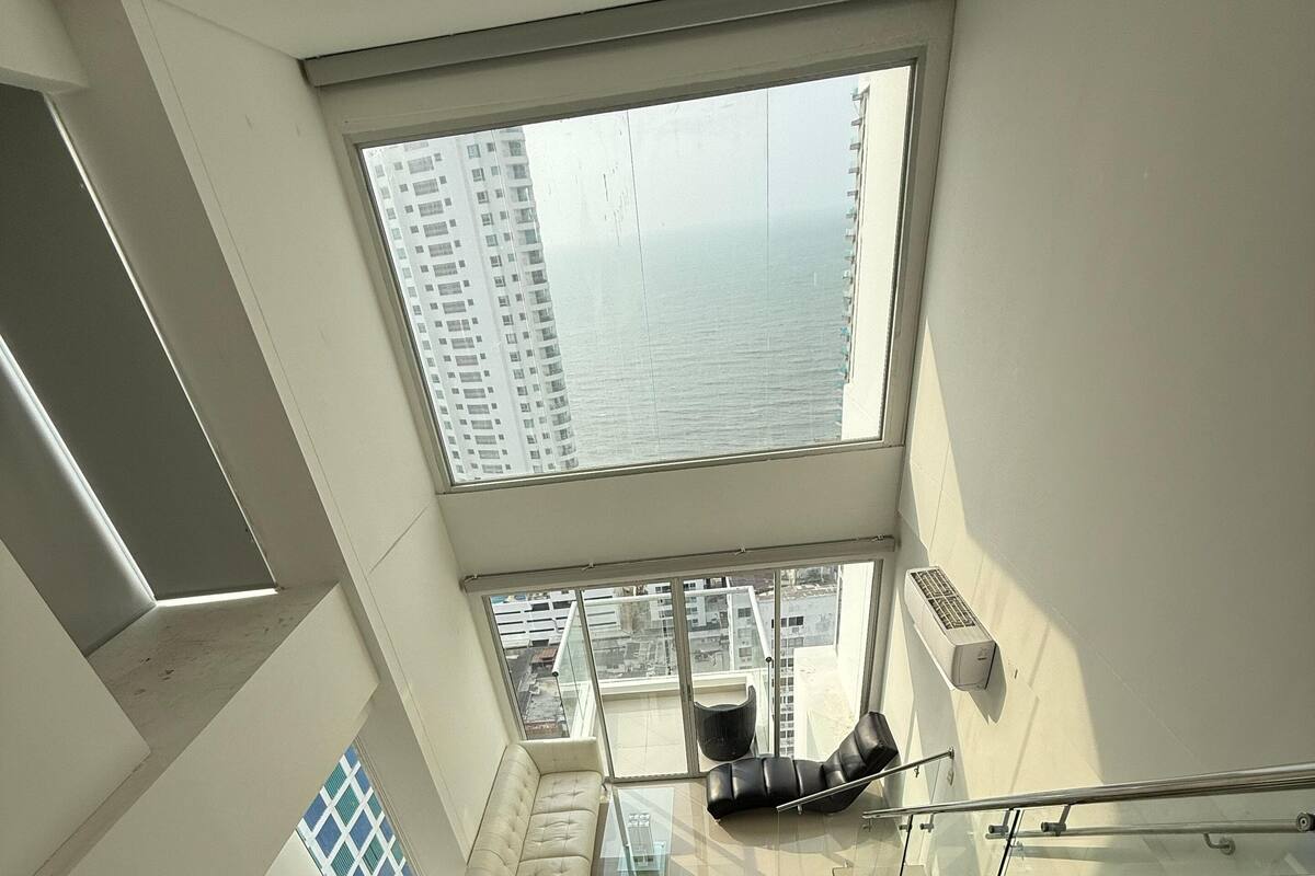 A high-rise apartment with a kitchen, dining area, and a large balcony with a city view.