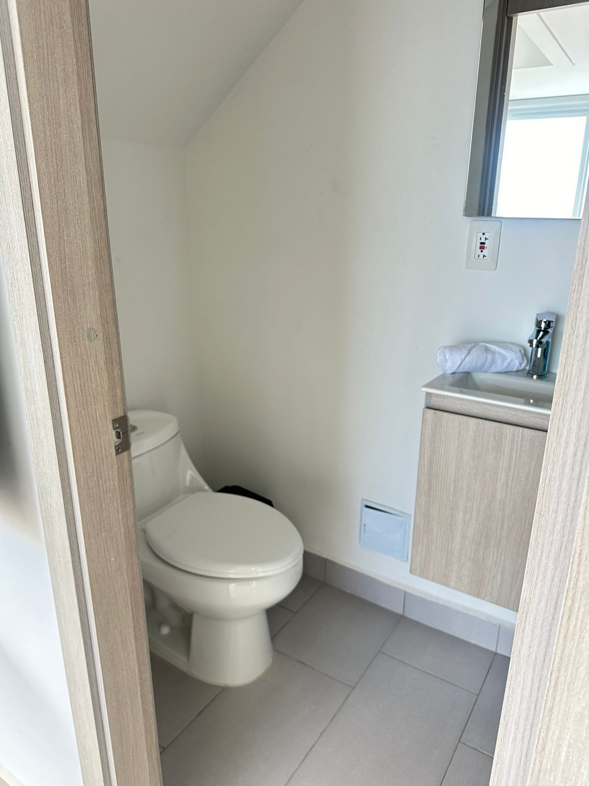 Un baño pequeño y limpio con inodoro, lavamanos y espejo.