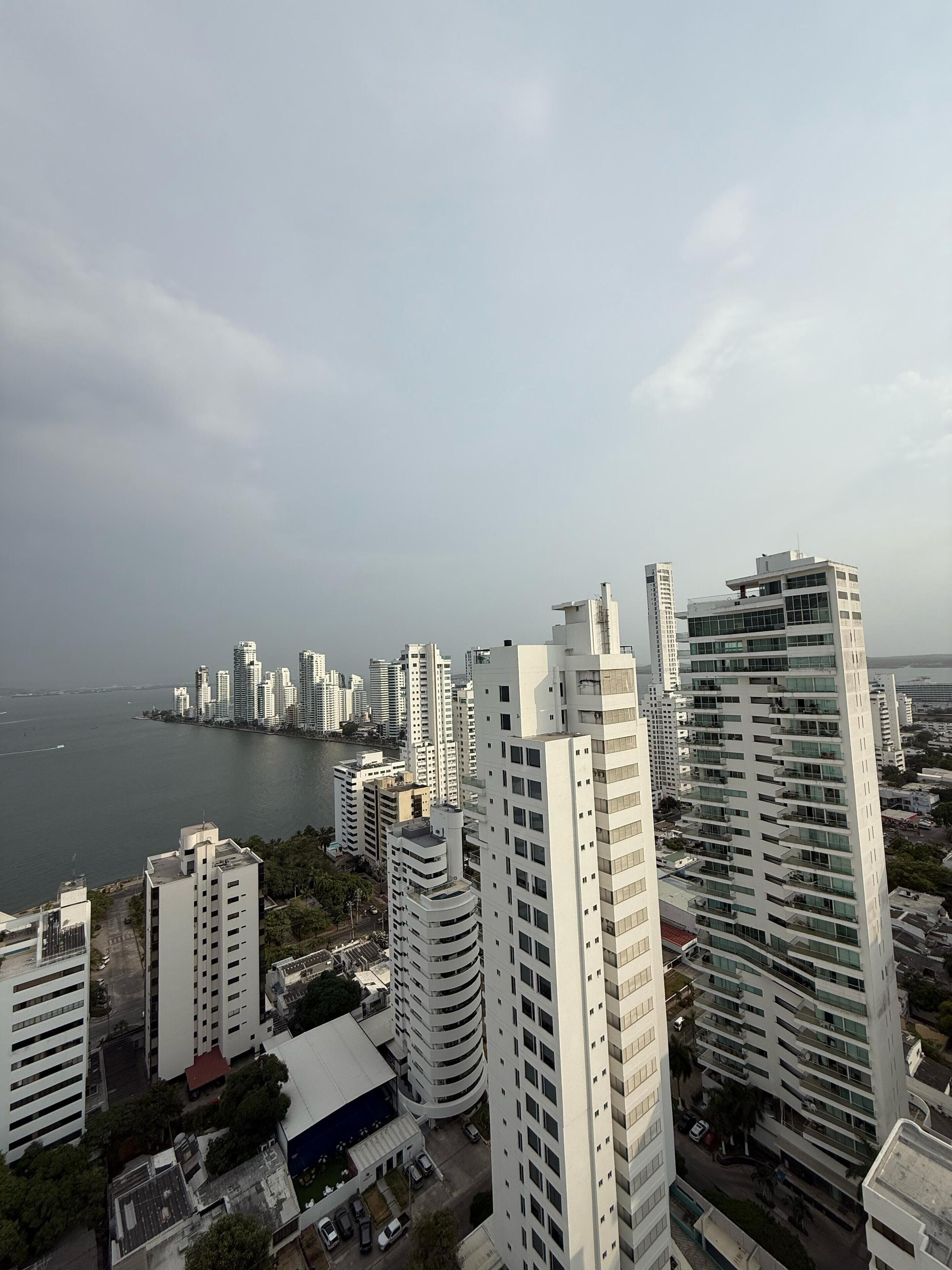 A high-rise urban area with modern buildings, a river, and a clear sky.