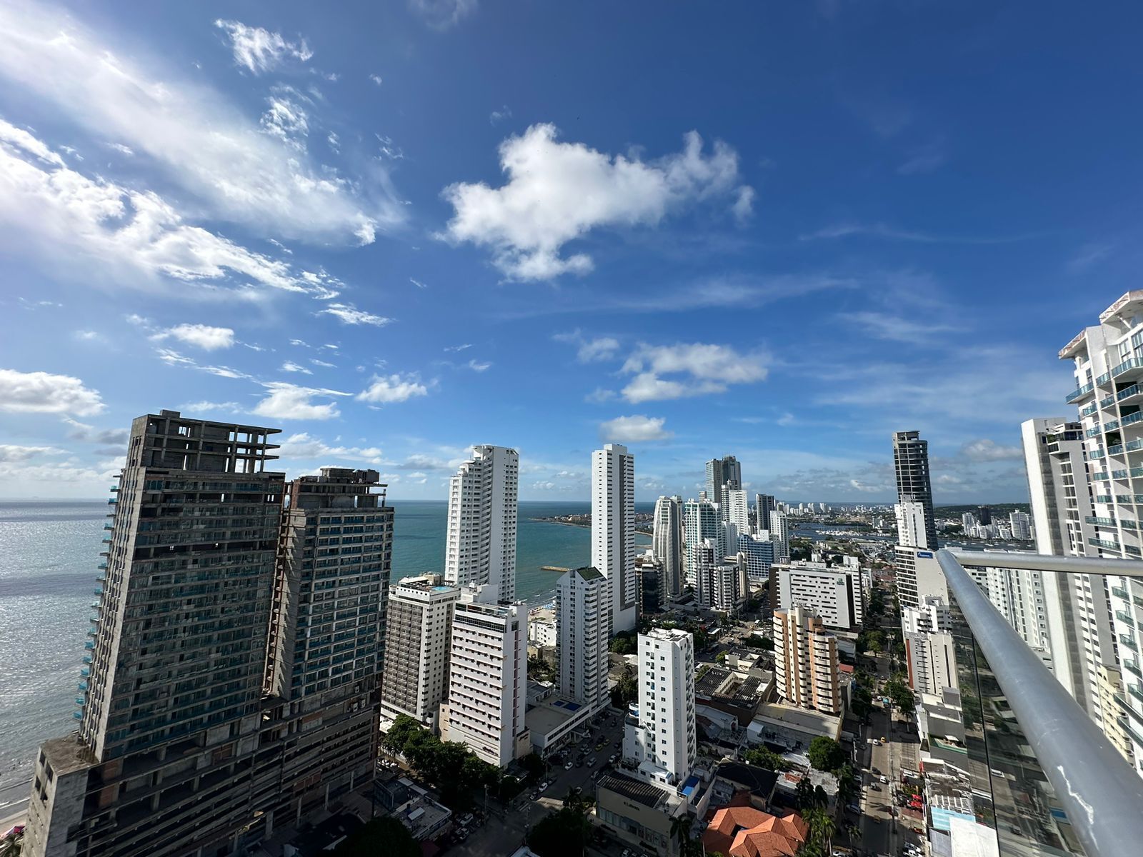 A high-rise urban area with multiple buildings, including a mix of residential and commercial structures, and a view of the sea.