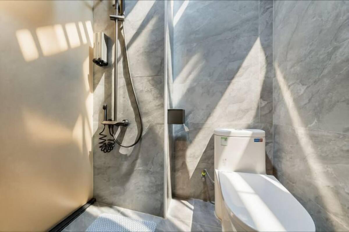 Un baño moderno con ducha, inodoro y paredes de mármol.