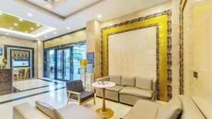 Un hall d’hôtel comprenant un comptoir d’accueil, un espace salon et un grand mur orné d’un panneau décoratif.