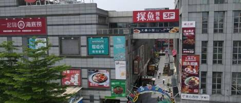 A commercial building with multiple storefronts and signage, including a prominent red sign with white characters.