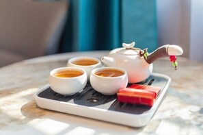 Una tetera con tres tazas de té sobre una bandeja.