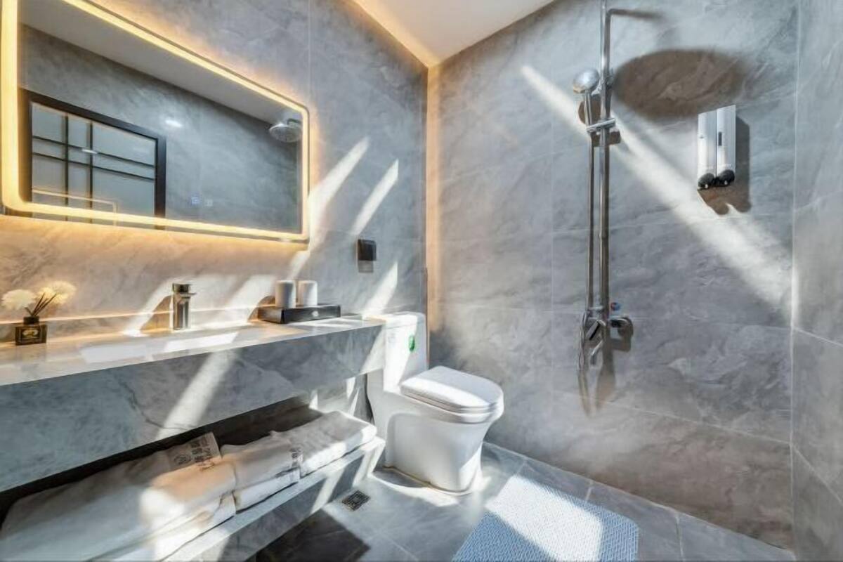 Un baño moderno con lavamanos de mármol, inodoro y ducha.
