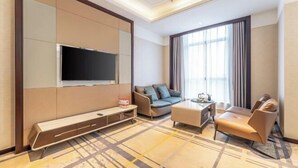 A modern hotel room with a flat-screen TV, a sofa, a coffee table, and a large window with curtains. - Shuiyi Jianianhua Hotel (Juancheng)