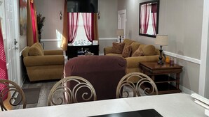 Una sala de estar moderna con un sofá, una mesa de comedor y una zona de cocina con estufa.