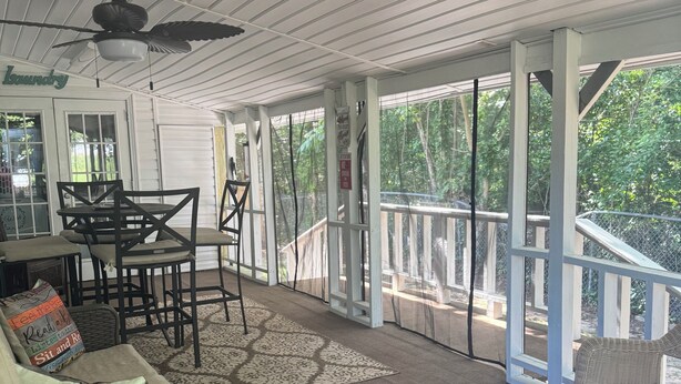 Un espacio al aire libre techado con ventilador de techo, una mesa con sillas y un sofá.