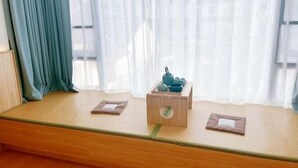A room with a tatami mat seating area, a wooden side table, and a window with sheer curtains. - Zhouzhuang Jingou Linhe Bieyuan Chinese Inn (Kunshan)