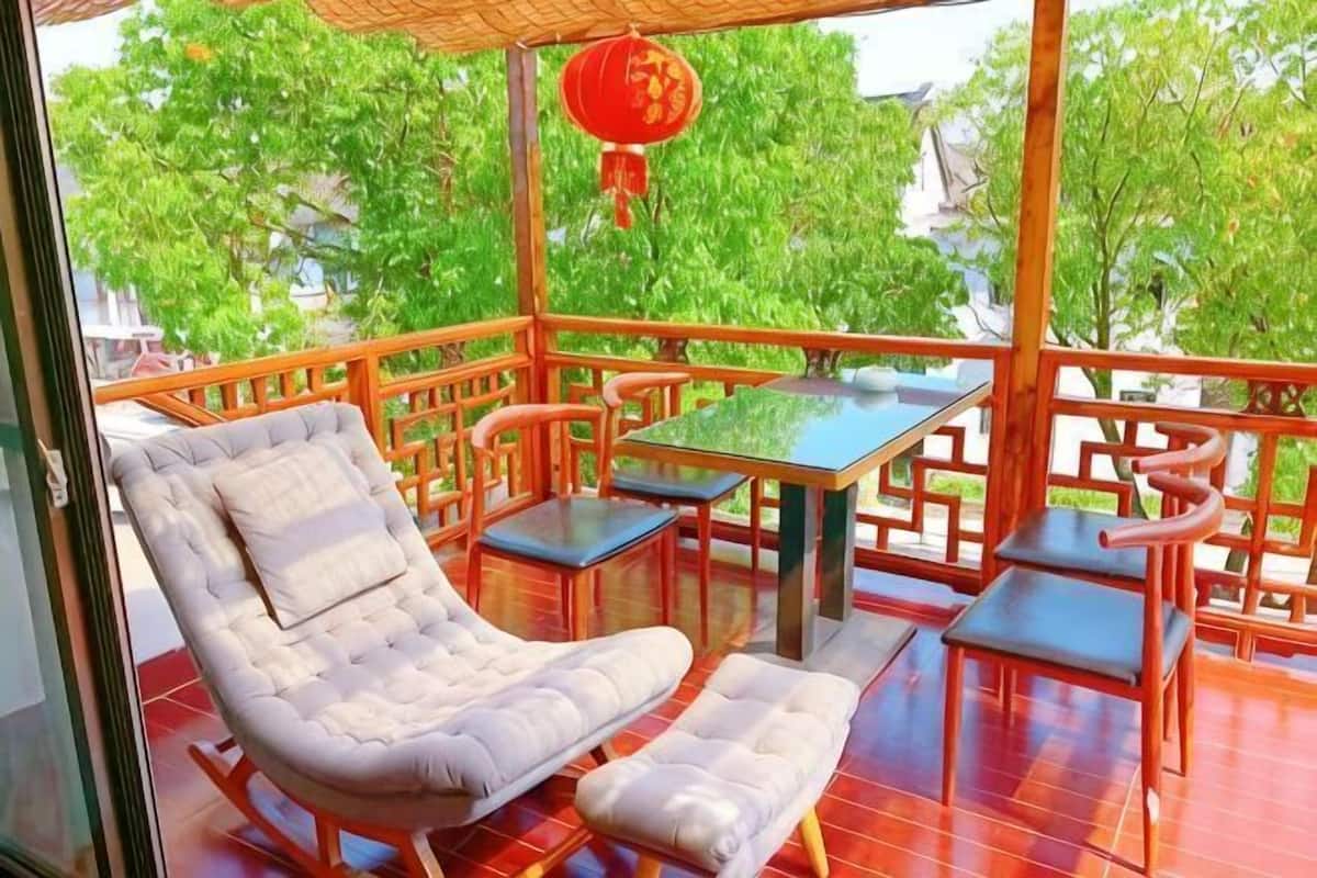 Un balcon agrémenté d’un fauteuil rembourré, d’une petite table et d’un pouf assorti.
