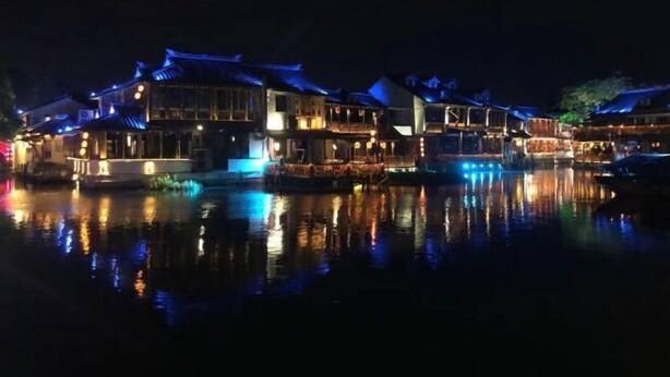 A traditional building with multiple levels and a reflection in the water. - Zhouzhuang Jingou Linhe Bieyuan Chinese Inn (Kunshan)